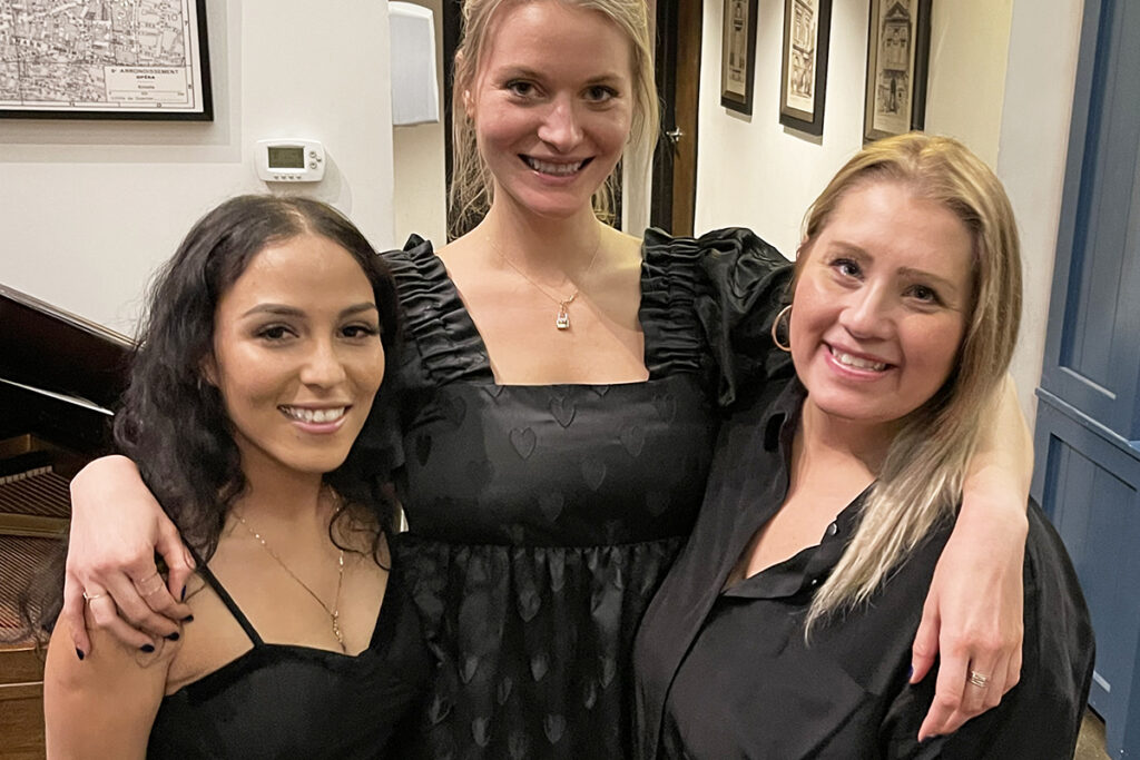 Trio of team members posing together and smiling at holiday party.