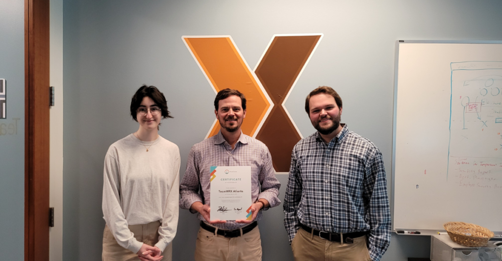 Justin Rainer holding TeamWRX's Certificate of Accessibility with WheelChariot's Gabriel Jones and Tori Stopford on either side of him